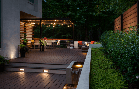 Contemporary backyard renovation features an impressive tiered Trex deck with a modern cantilevered