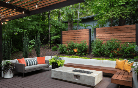 Contemporary backyard renovation features a gorgeous tiered Trex deck with a modern concrete fire pit