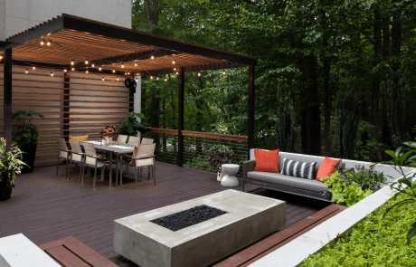 Custom backyard renovation features a covered outdoor living space with a modern cantilevered aluminum pergola and attached decorative cedar slat wall