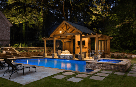 Luxurious outdoor living space with custom swimming pool and stacked stone spa with waterfall