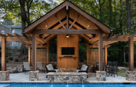 Custom Post and Beam pool house with stacked stone pedestals sits pool side and boasts
