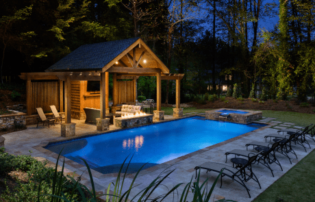 High-end, custom-built, outdoor living space with rectangular swimming pool and stacked stone spa with waterfall spillover