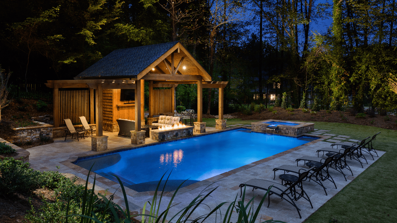 High-end, custom-built, outdoor living space with rectangular swimming pool and stacked stone spa with waterfall spillover