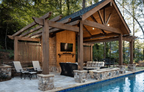 Custom backyard renovation features a gabled Post and Beam pool house with stacked stone pedestals
