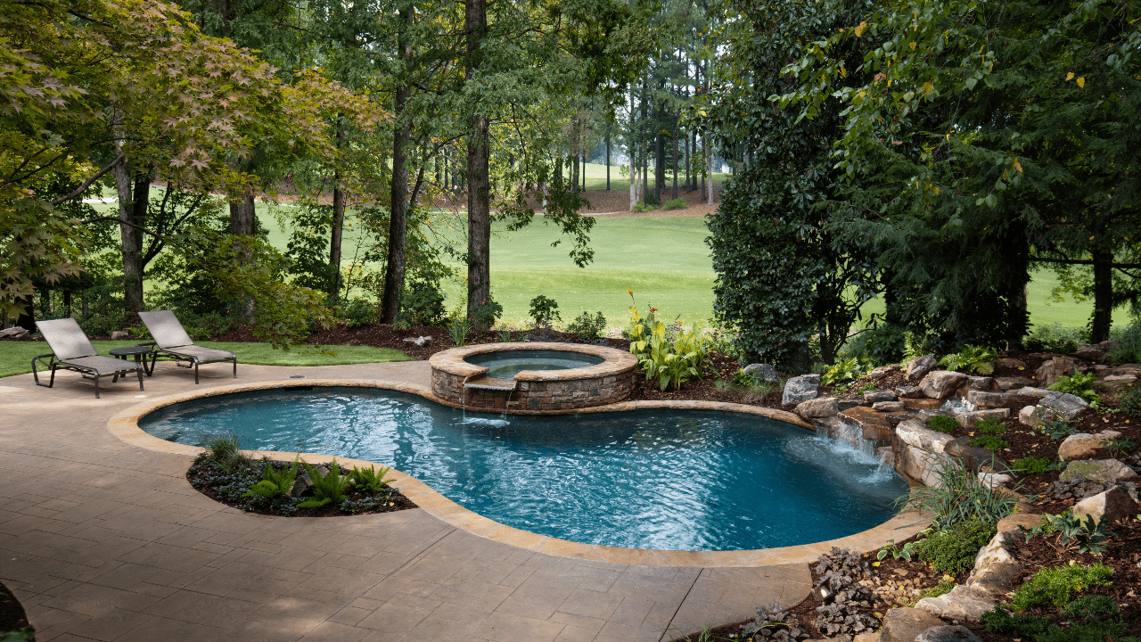 Backyard renovation includes a decorative stamped concrete patio and free form custom swimming pool with a stacked stone raised spa, waterfall spillover, underwater stone bench, flagstone coping and boulder waterfall.
