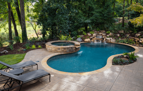 Backyard renovation includes a decorative stamped concrete patio and free form custom swimming pool with a stacked stone raised spa, waterfall spillover, underwater stone bench, flagstone coping and boulder waterfall.