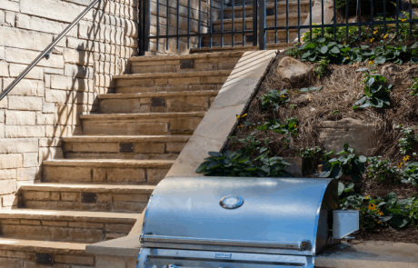 Custom stacked stone staircase leads from the driveway to the pool patio and outdoor grilling station with flagstone countertops and a built-in grill.