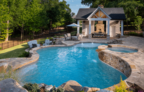 Custom pool design includes multi-level flag stone patios with a raised spa and water slide on the terrace level, stacked stone steps lead to the pool house which features a covered cabana with outdoor stacked stone fireplace and pizza oven combination, entertainment area, pool house bathroom and storage room. The lower level includes a modern style wood burning fire pit and lush green lawn.