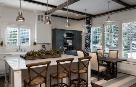 Eat in kitchen features a large island with seating, farmhouse sink, white shaker cabinets, marble counter-tops, white subway tile backsplash, brown hardwood floors, polished nickel lighting and Viking appliances.