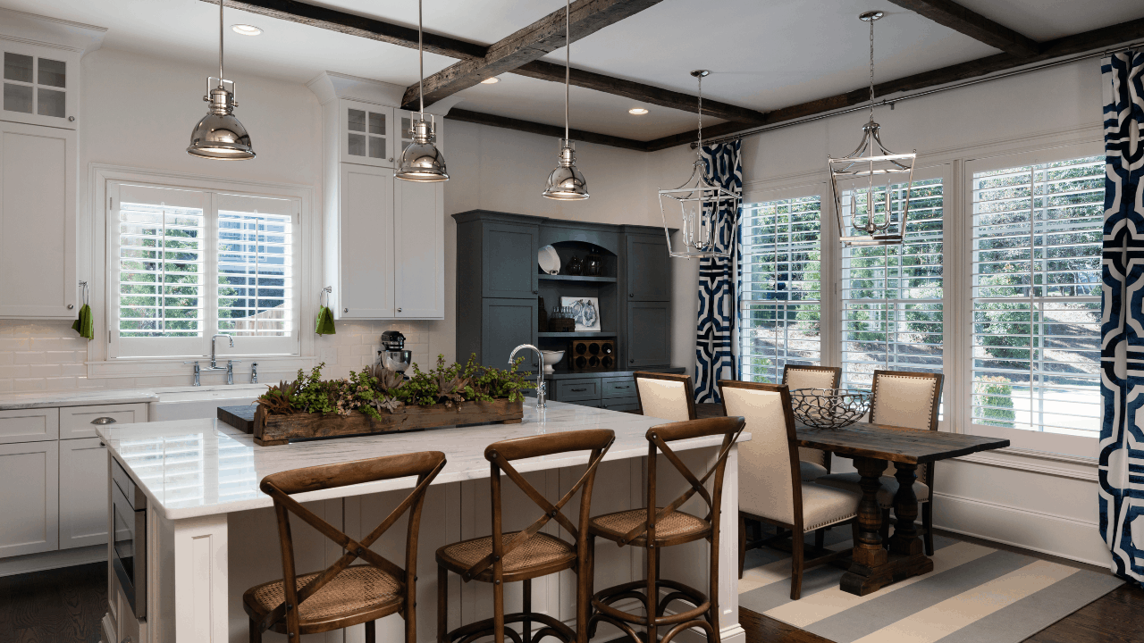 Eat in kitchen features a large island with seating, farmhouse sink, white shaker cabinets, marble counter-tops, white subway tile backsplash, brown hardwood floors, polished nickel lighting and Viking appliances.