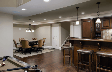 Traditional open concept basement remodel includes a custom bar with cherry cabinets and bar top, full size appliances and leather bar stools that opens up to a game room, billiard room, and home theater making it the perfect place for entertaining.
