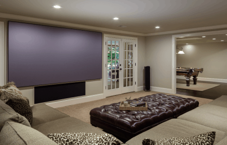 The home theater in this basement remodeling project is relaxing and stylish with comfortable seating and a seamless indoor-outdoor connection to the outdoor living space and adjoining bar area, game room and billiard room