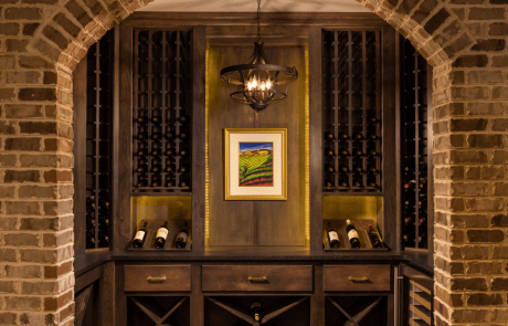 This stunning wine closet was custom built using Mt. Rushmore' Natural Clay brick veneer and includes custom stained cabinetry and shelving for storing and displaying 400 bottles of wine. Rope lighting and a 4-light antique bronze candelabra provides subtle lighting while a wine cooler located on the right side ensures that chilled bottles maintain temperature.