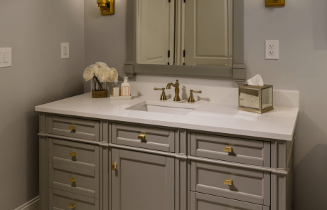 This beautiful bath remodel features a transitional style vanity in Urban Gray with satin brass fixtures, undermount sink and a “Snow-White quartz” counter-top.