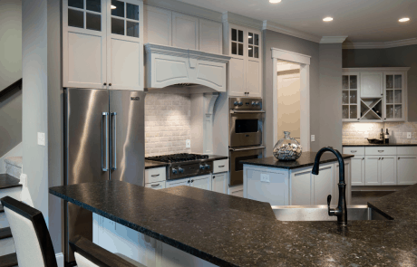The spacious modern transitional kitchen features an eat-in-kitchen, breakfast bar, island, and separate coffee station with black leathered granite countertops, floor to ceiling white shaker cabinets with black hardware and stainless-steel appliances.