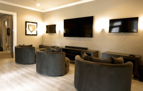 This state-of-the-art video game room features multiple mounted TVs and gaming stations with ample storage, comfortable swivel arm chairs in chocolate brown, the perfect combination of accent lighting and the latest in audio technology.