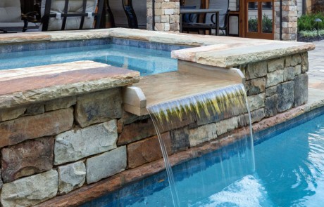 rectilinear swimming pool features a stacked stone raised spa with spillover and Tennessee flagstone coping