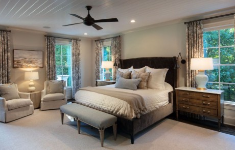 Transitional style, neutral colored master bedroom painted in Benjamin Moore’s Edgecomb Gray with white trim work, white painted tongue-and-groove ceiling, secret hidden door, dark bronze wall sconces and ceiling fan, brown hardwood floors and designer finishes.