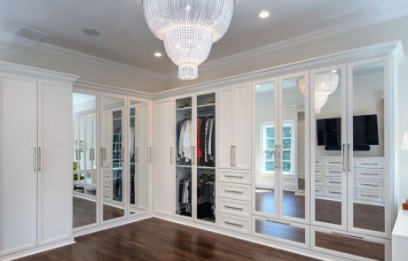 Second story addition includes large private dressing room and master closet with ample storage, white custom cabinetry and mirrored doors with polished nickel hardware and stunning two-tier chandelier. Walls are painted in Dove Wing by Benjamin Moore.
