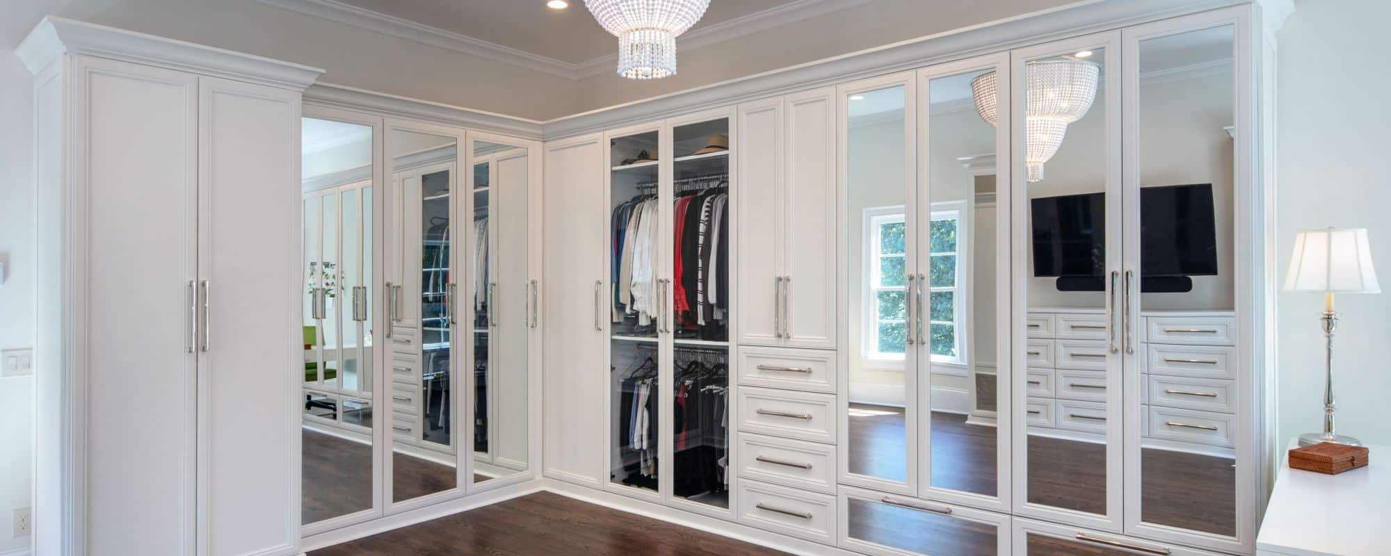 Second story addition includes large private dressing room and master closet with ample storage, white custom cabinetry and mirrored doors with polished nickel hardware and stunning two-tier chandelier. Walls are painted in Dove Wing by Benjamin Moore.
