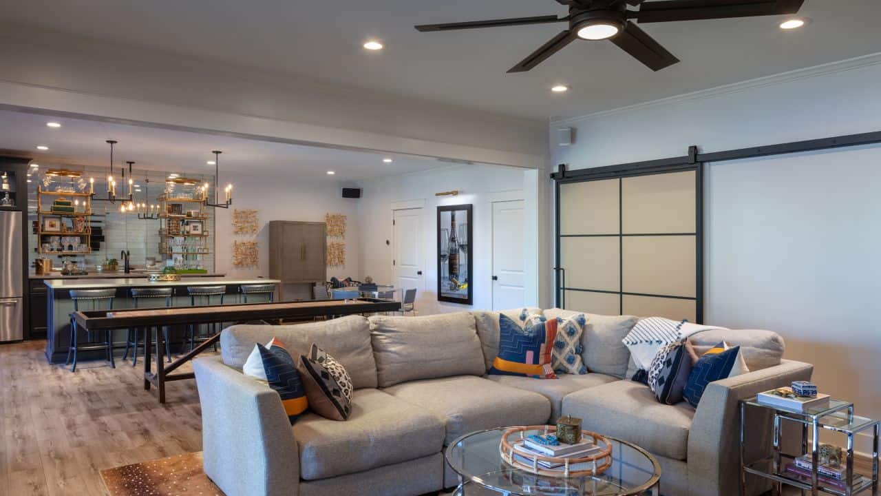 Basement Remodel with Kitchen, Bar Island w/Seating, Charcoal Cabinets, Caesarstone Quartz Countertops, Stainless Steel Appliances, Mirrored Backsplash, Floating Shelves, Brass Pendant Lights, Custom Shuffleboard Table and Metal & Glass Barn Doors.