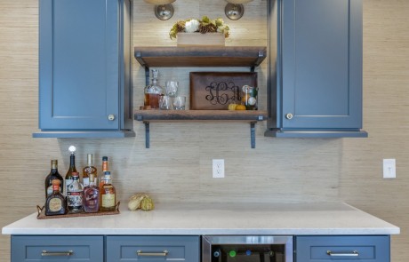 custom designed home beverage station maximizes the kitchen’s efficiency and boasts a built-in wine fridge, gray shaker cabinets with plenty of storage, white quartz countertops
