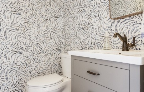 Chic powder room remodel with fun, bold wallpaper features a 24” gray vanity with white marble countertop