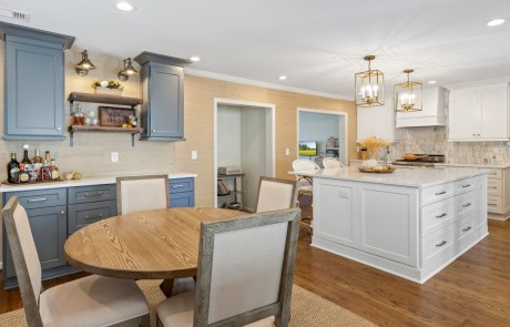 large center island with white quartz countertops, ample storage and bar seating is the hub of the home in this white shaker kitchen remodel