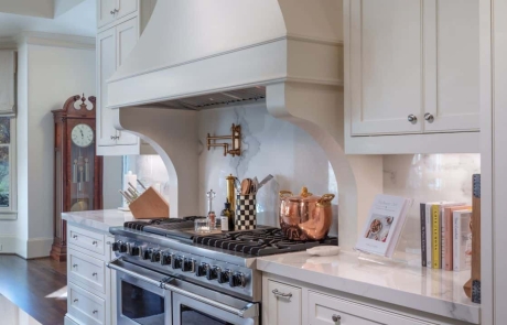 Custom Kitchen Remodel with Polished Kalos Bianco Porcelain Countertops, White Custom Inset Cabinetry, 60” Viking Dual Range, Custom Vent Hood, Solid Surface Slab Backsplash, Waterstone Pot Filler in Satin Brass