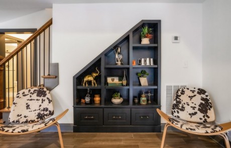 Custom basement remodel finished with custom under stair built-ins & drawers in black and a pair of mid-century modern tripod chairs upholstered in authentic hide fur.