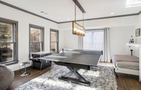 This custom designed basement game room is incredible with white custom murphy beds and built-ins for storage, a ping pong table, pinball machine and fun faux black tip sheepskin rug.