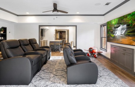 A basement home theater was a must in this custom basement remodel complete with comfortable gray leather stadium seating, large mounted flat screen TV and a high performing audio system.
