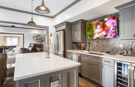 This gorgeous open-concept finished basement offers plenty of entertaining space with four distinct living spaces including a contemporary gray and white kitchen and bar area with full kitchen, wine fridge and mounted tv, home theater and family room, a game room with hidden murphy beds and a wine tasting room.