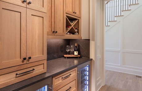 Adjacent to the kitchen is a full-service butler’s pantry with charcoal gray quartz countertops and matching solid surface backsplash, light stained Shaker cabinets and drawers with black hardware and dual under-counter beverage centers.