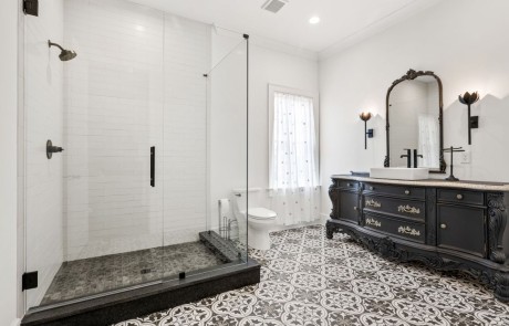 Luxurious bathroom addition with black custom vanity, grey porcelain victorian tile floor, oversized glass shower enclosure with black pearl leathered granite shower curb.