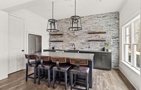 Custom built basement bar with full kitchen, rustic leather bar seating, black shaker cabinets with large black & pewter antique pulls, reclaimed brick backsplash, black pearl granite countertops, & stainless steel appliances.