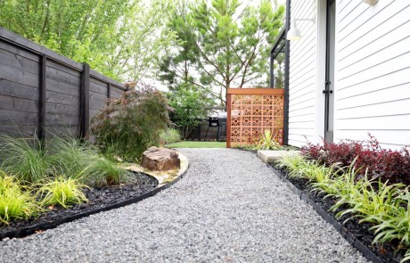 Zen garden walkway with gravel path bordered by modern, colorful plantings and ornamental grasses.