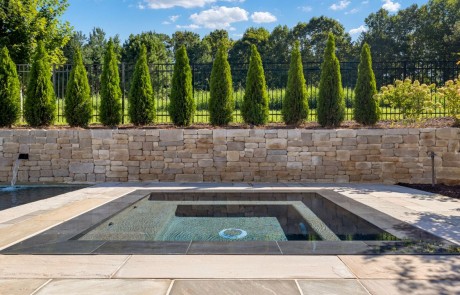 Stunning knife-edge perimeter overflow spa, outlined in onyx-colored coping, creates a smooth mirror-like surface, and serves as a focal point in this exclusive swimming pool design.