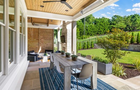Covered outdoor living space features a French Pattern Cut Sandstone patio with separate outdoor dining room and seating area, modern limestone fireplace, tongue & groove ceilings & decorative screen walls.