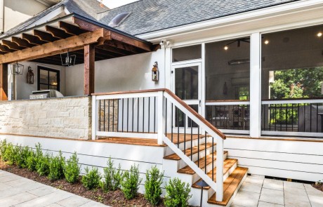 Sophisticated and elegant outdoor living addition with large screened-in-porch, separate cedar grilling deck, modern design pergola with sleek standing seam metal roof, and neutral porcelain paver walkway.