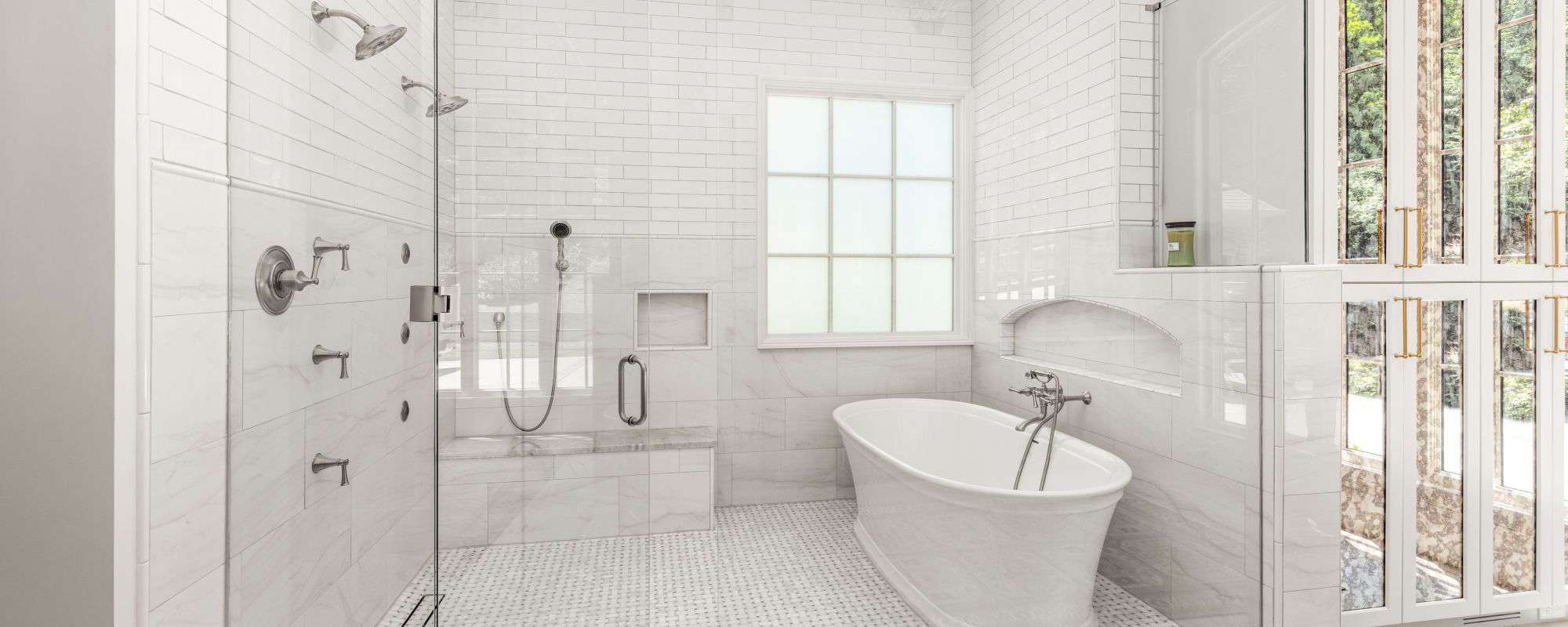 Spa-inspired bathroom features custom wet room with walk-in shower, dual shower heads, built-in shower niche, white freestanding tub, polished nickel bathroom fixtures and mosaic tile flooring.