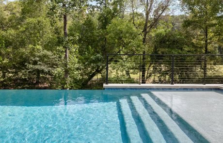 Ray-18-Gallery Infinity-edge pool with large tanning ledge and full-length entry steps leading into crystal-clear water, designed by Boyce Design + Build in Duluth, Georgia.