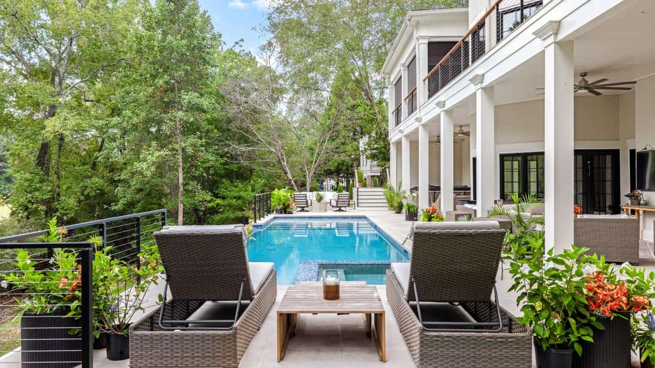 Contemporary poolside living with a sleek infinity-edge pool, limestone patio, and covered lounge area by Boyce Design + Build