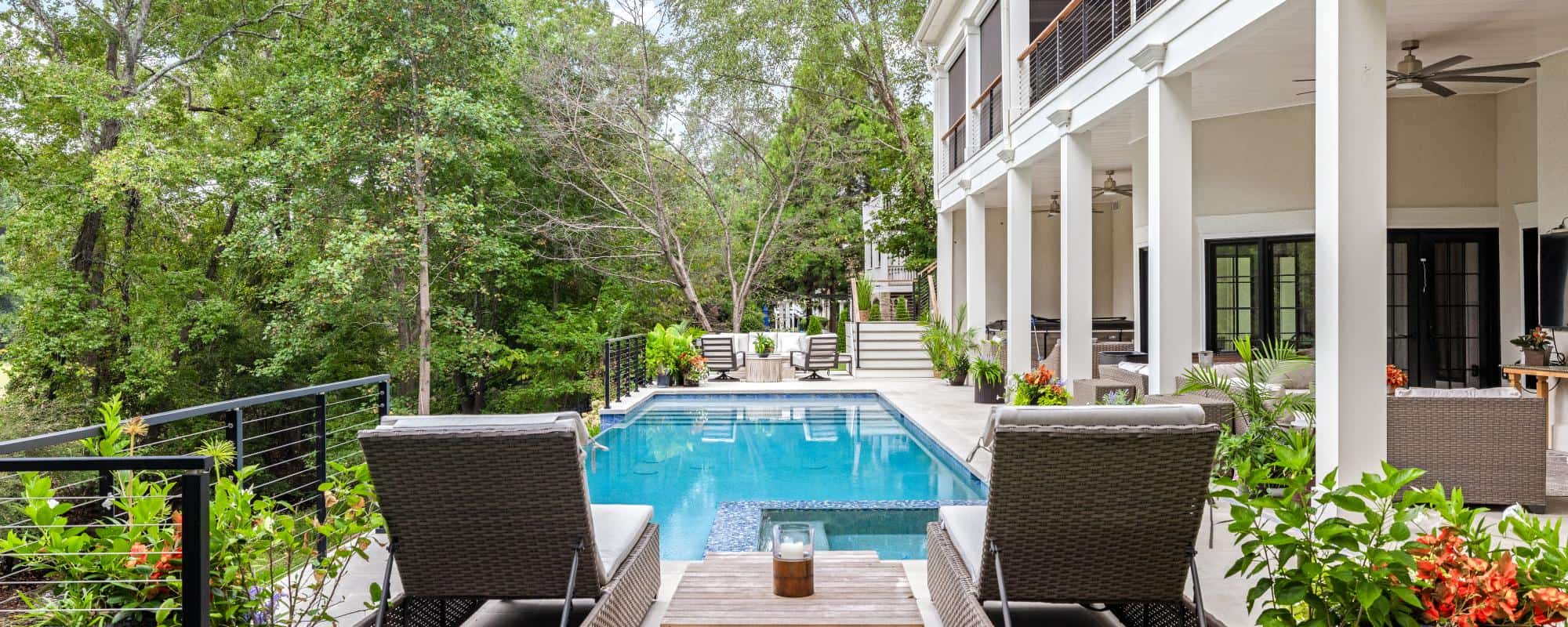 Contemporary poolside living with a sleek infinity-edge pool, limestone patio, and covered lounge area by Boyce Design + Build