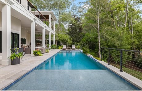Ray-46-Gallery Expansive infinity-edge pool with a large tanning shelf and sleek limestone decking creates a luxurious space for lounging, entertaining, and year-round outdoor living by Boyce Design + Build in Duluth, GA.