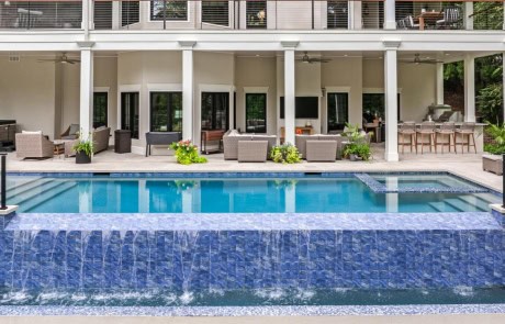 Ray-58A-Gallery Luxury infinity-edge pool with blue mosaic tile spillover wall and modern limestone patio.